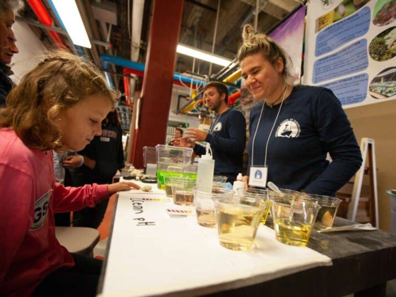 A young girl learns about ocean pH from a female scientist inside the GSO aquarium.